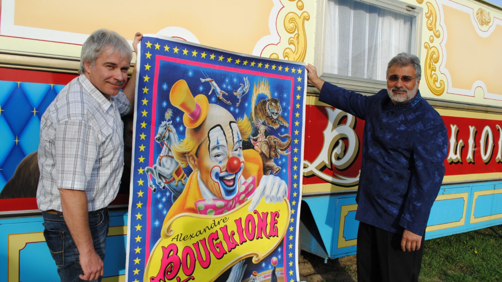Alexandre Bouglione et Pierre Mainil tenant une affiche de cirque devant une roulotte
