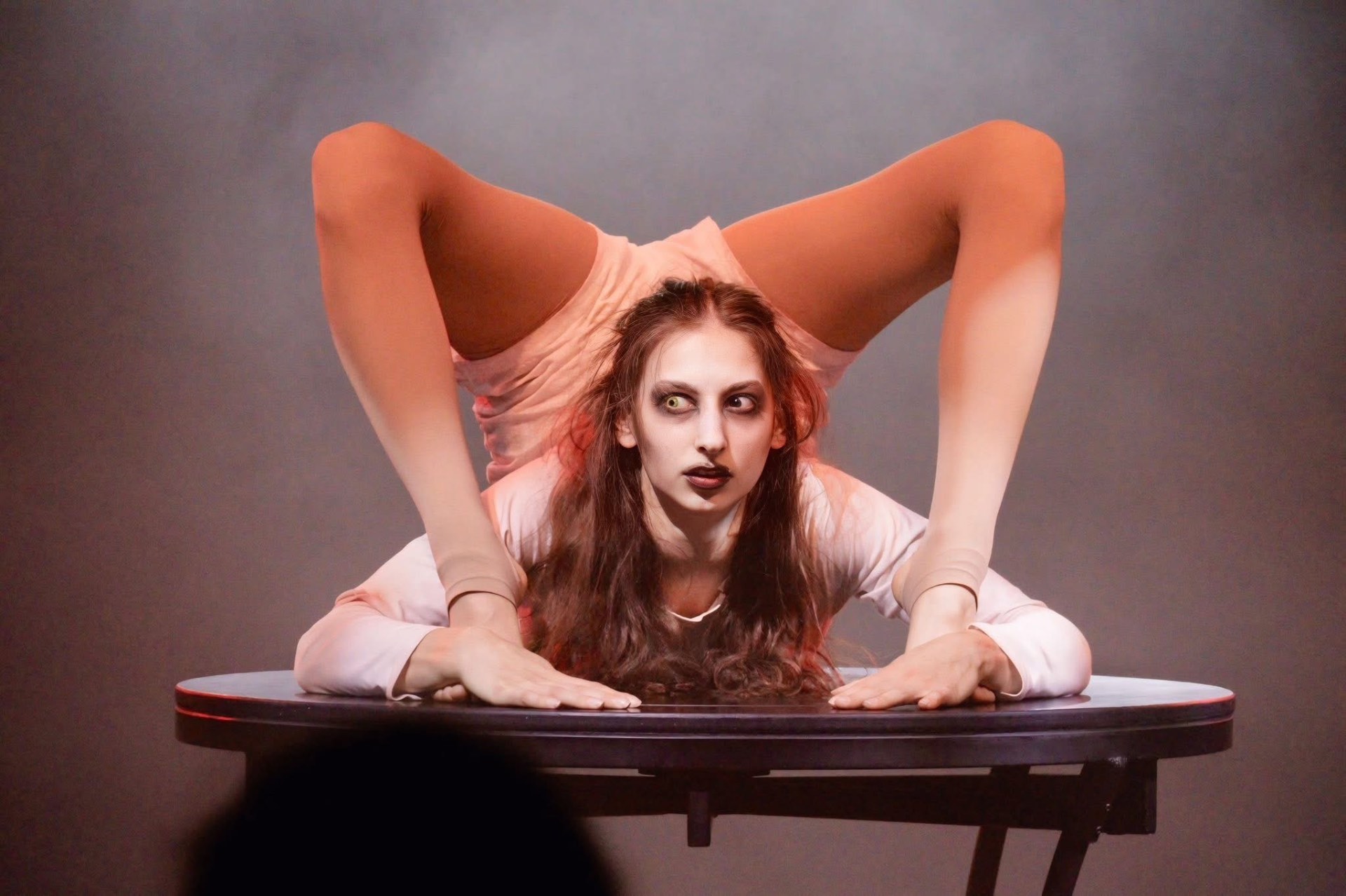 Contorsionniste au regard inquiétant sur une table, sous la lumière
